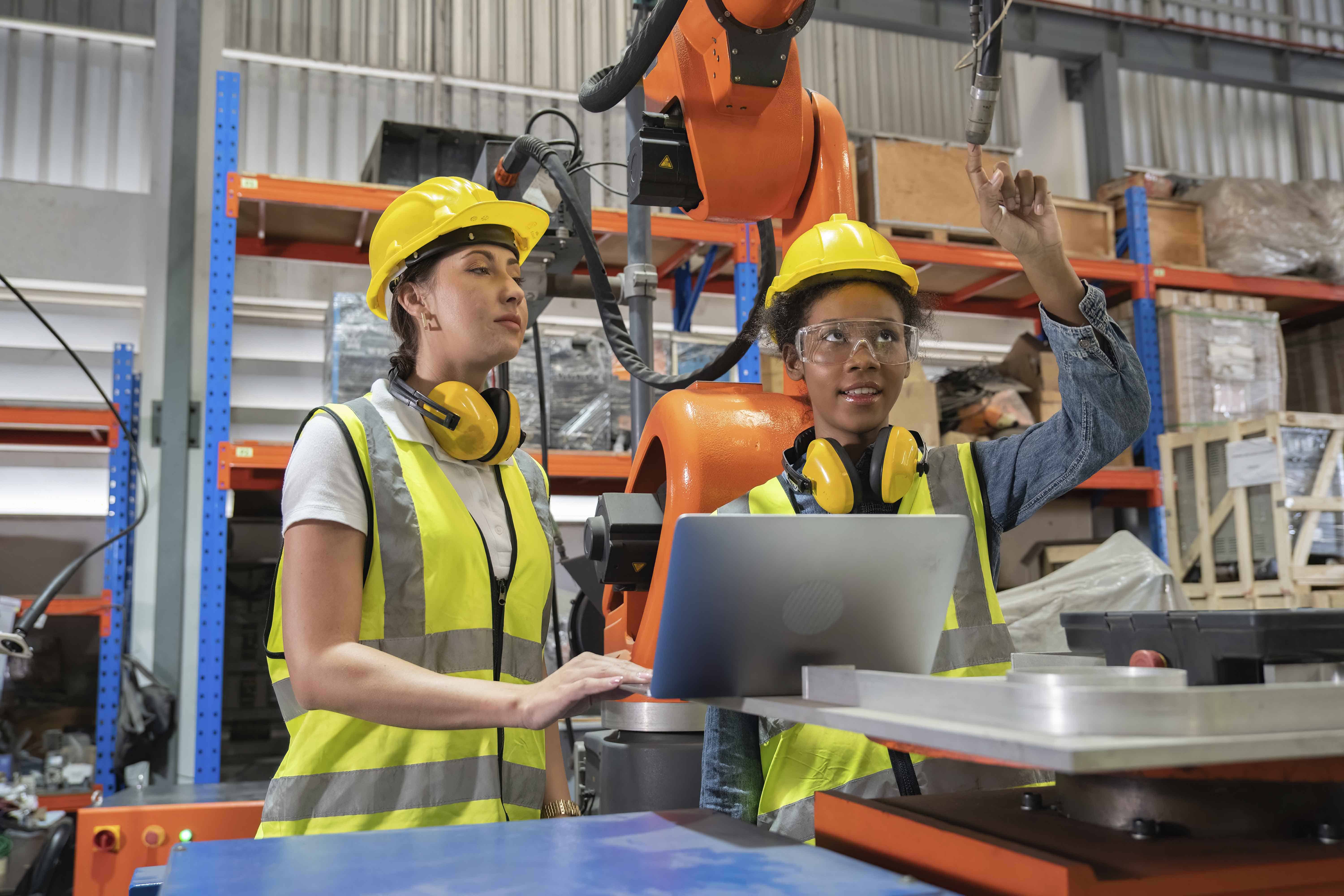 Women Engineer in factory using computer working on welding robotic arm testing programming