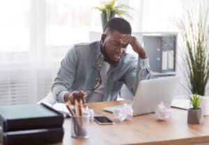 chico afro y dueño de pyme está molesto y estresado mirando su laptop
