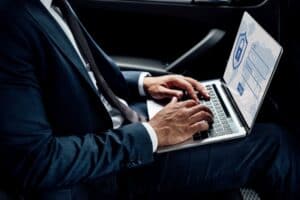 Un empresario blanco con traje revisa su laptop plateada y ve un inicio de sesión asegurado
