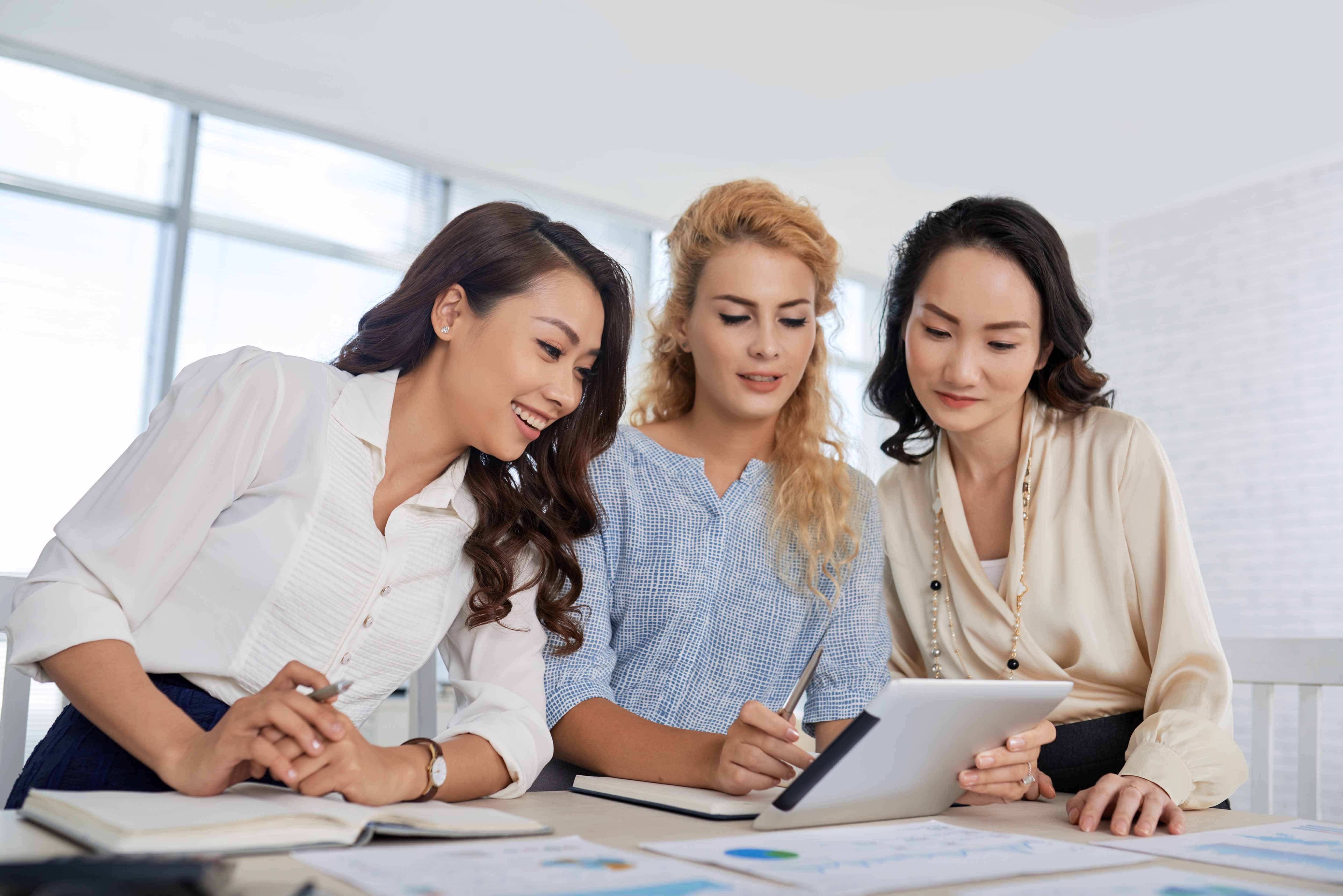 Multi-ethnic team of business women analyzing information on tablet computer